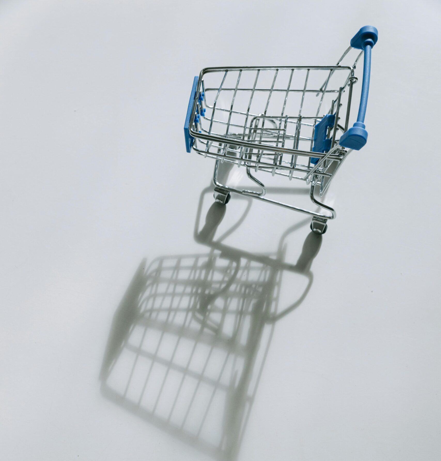 Empty shopping cart casting a shadow on white background.